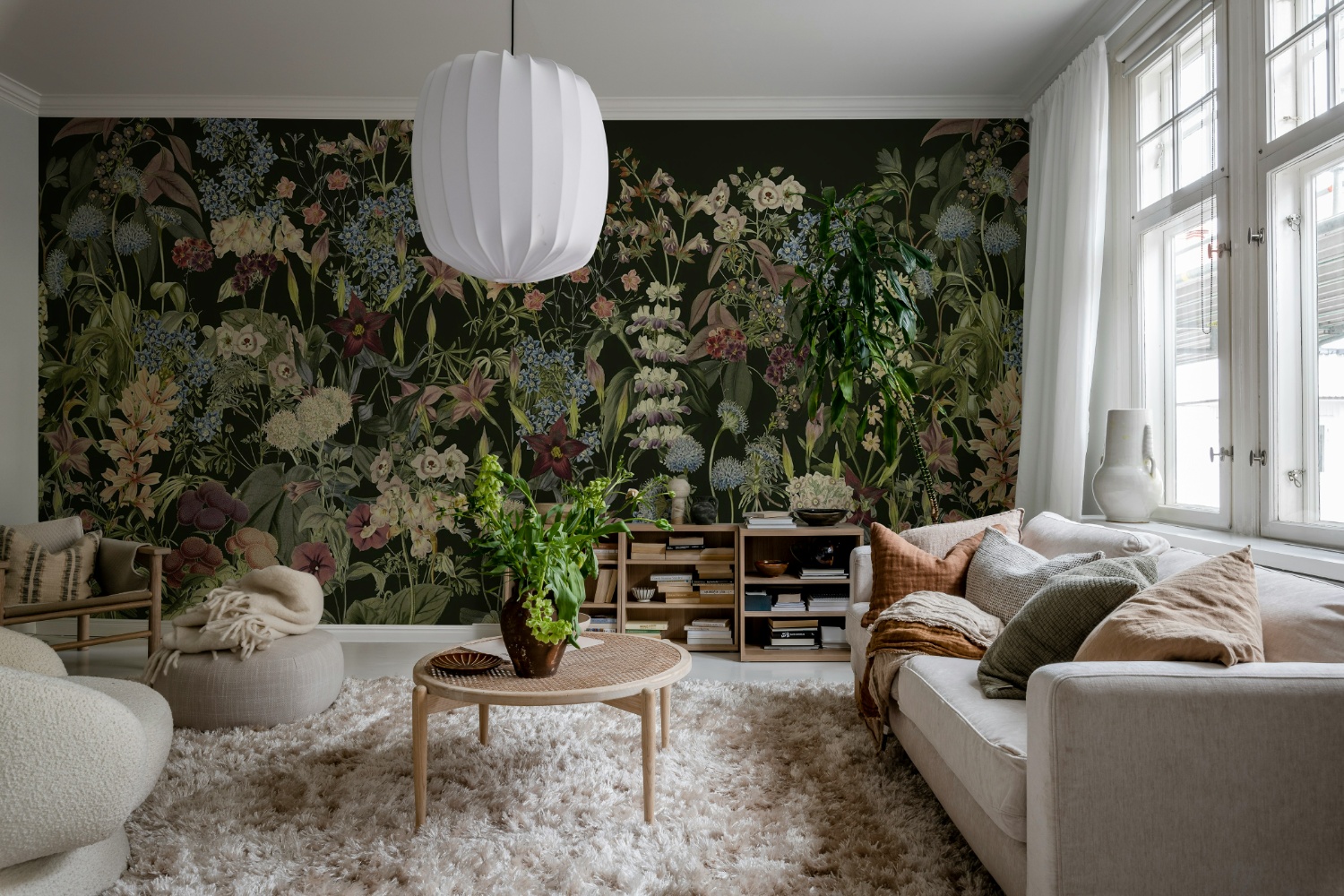 Black living room wallpaper featuring a dark floral mural wall paired with cream sofas, natural wood furniture, and soft neutral décor