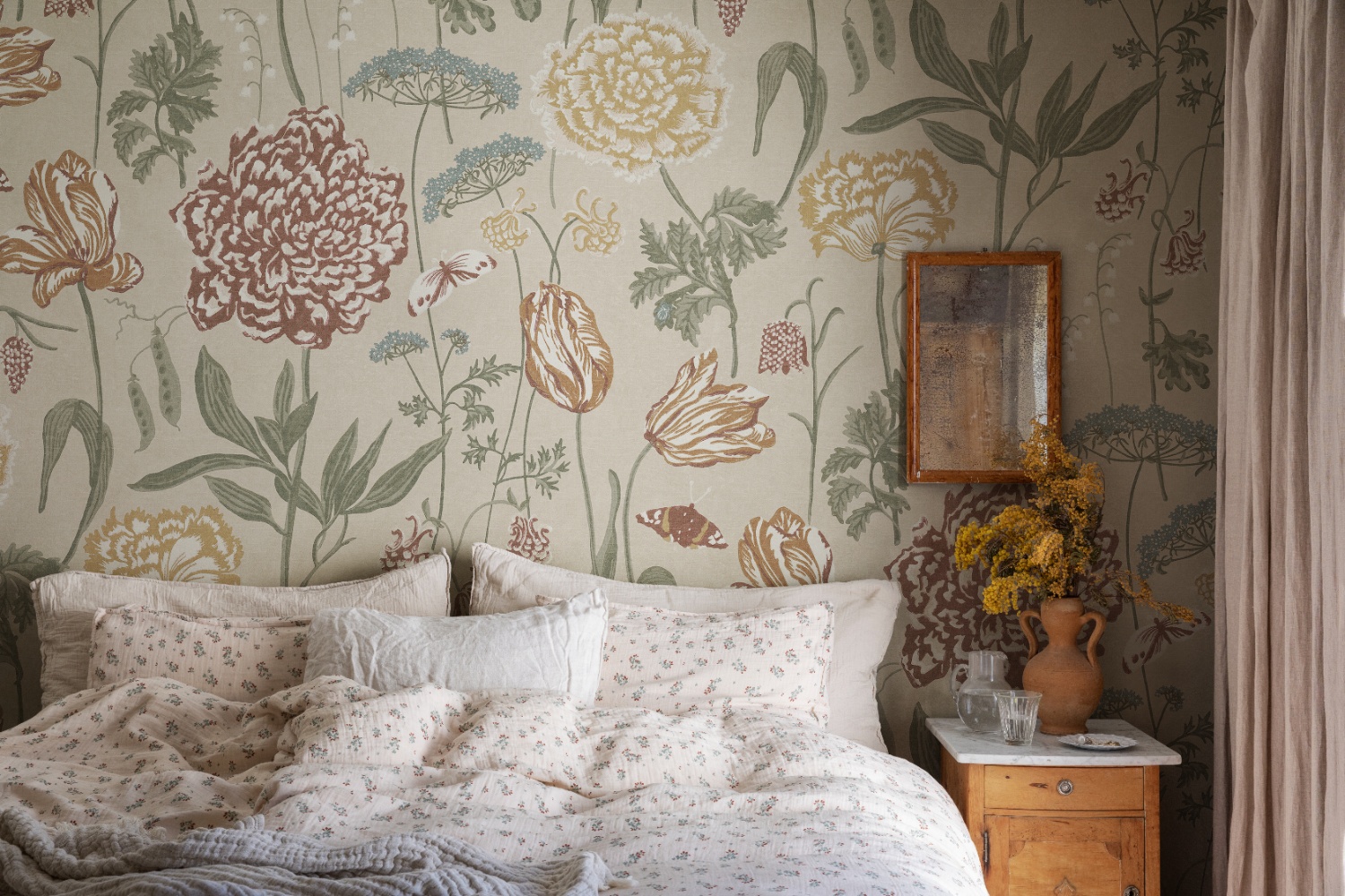 Neutral floral mural wallpaper in sand styled in a cosy bedroom