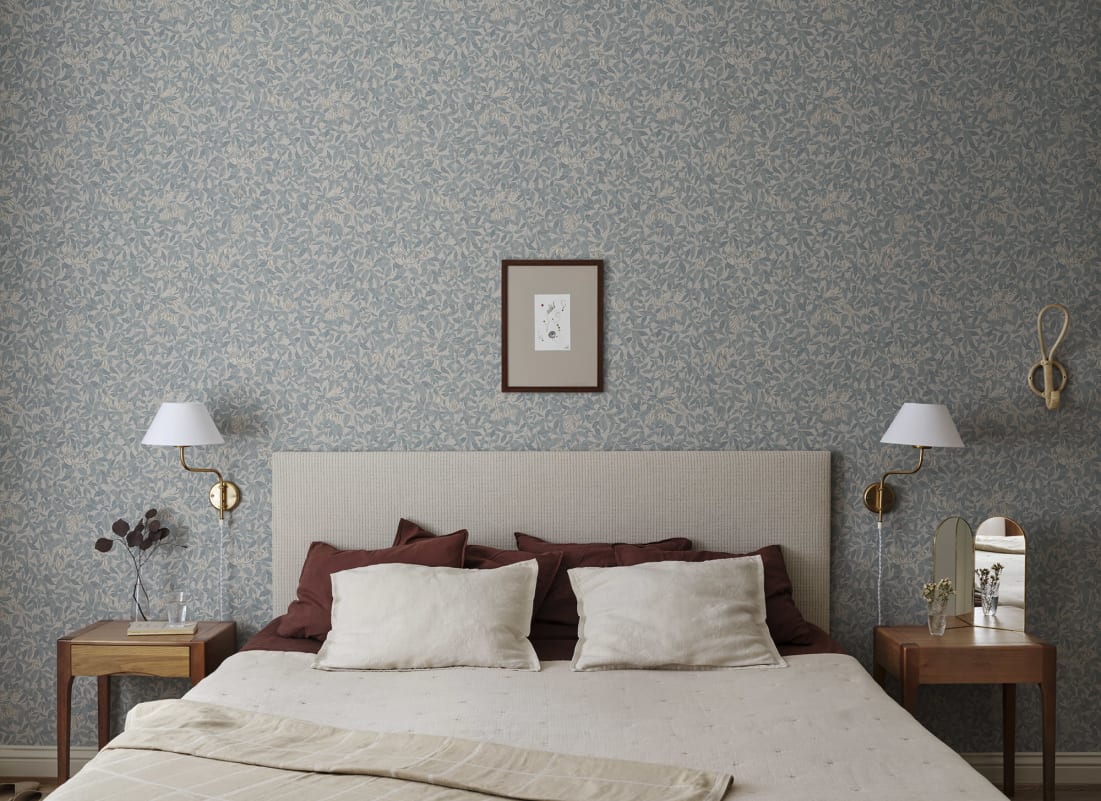 Linnea floral pattern cottagecore wallpaper in misty blue in cosy bedroom with white bed