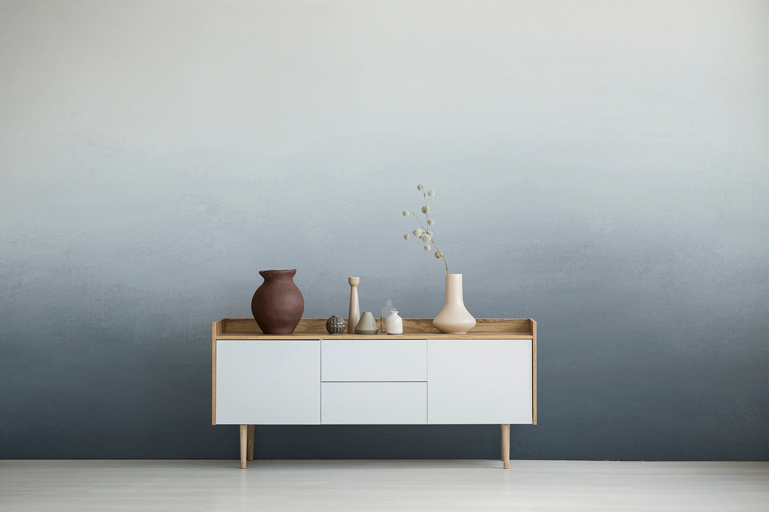 Ombre Mural Wallpaper in Blue with vases and decor items on a white sideboard