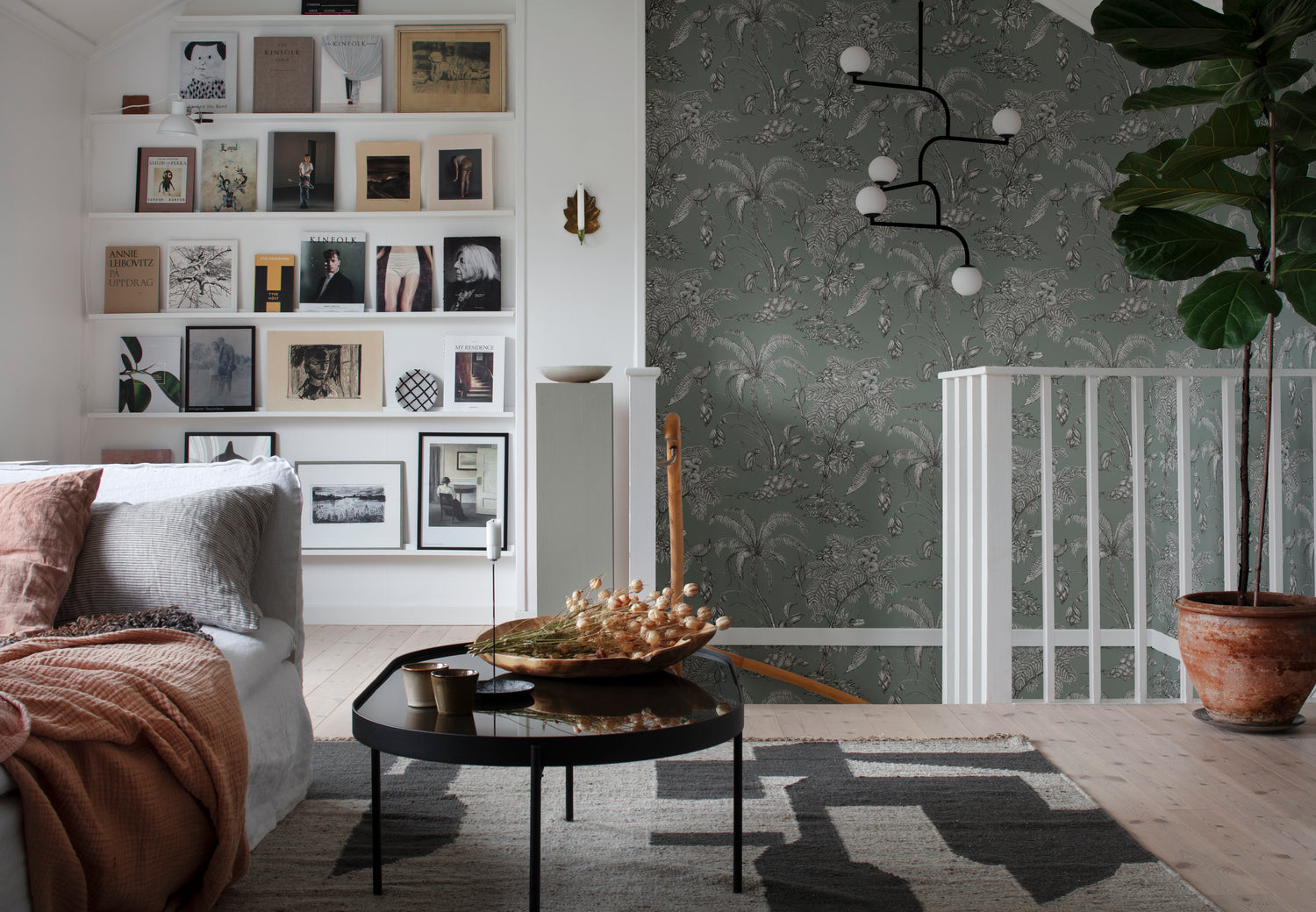 Tropical staircase wallpaper in sage green with white palms above a white stair balustrade in an open-plan living room