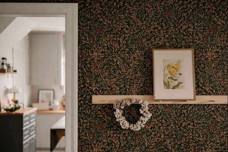 Dark botanical wallpaper with layered foliage in a charcoal entryway