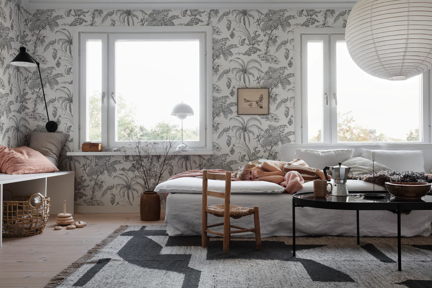 Black and white pattern wallpaper with tropical jungle illustrations applied in cozy living room